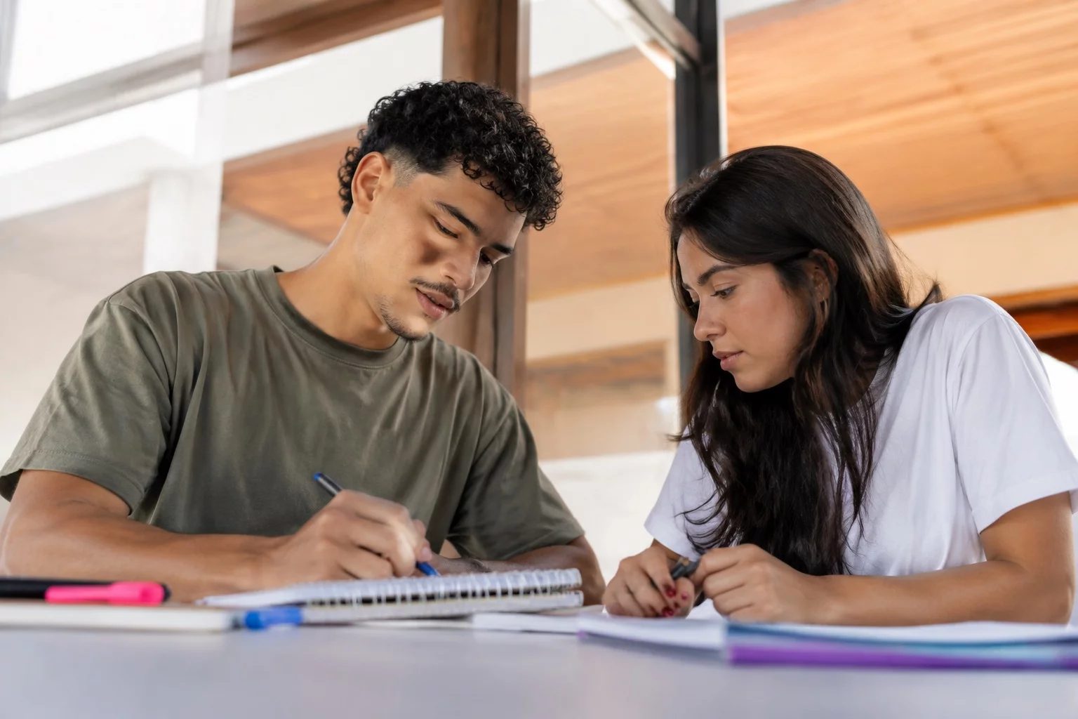 Dois estudantes preparando um debate com cadernos e marcadores